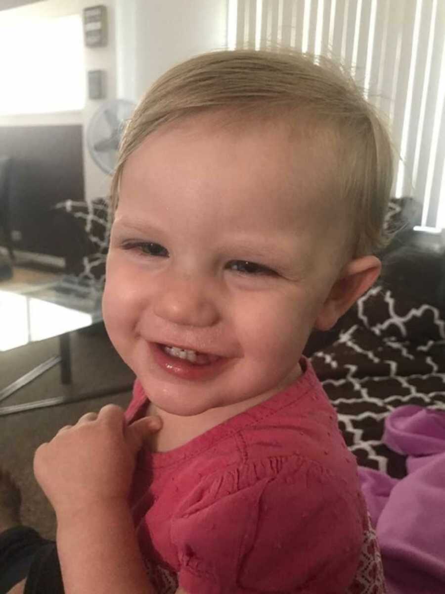 Little girl in pink shirt smiling on couch