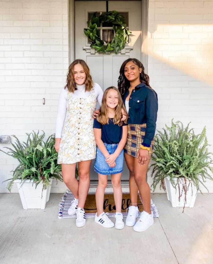 Three sisters standing outside front door of home