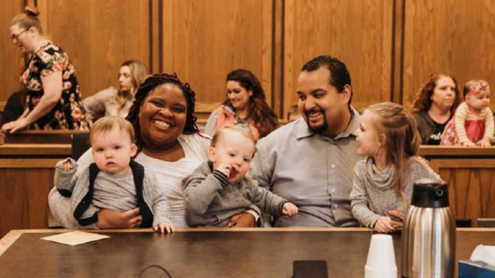 Adoptive family smiling together in courtroom