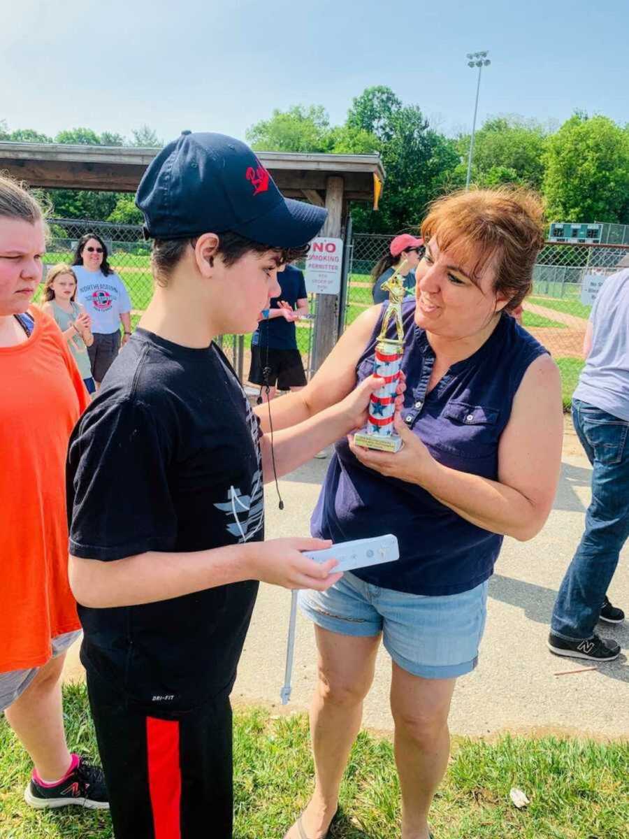 Boy with autism receiving sports trophy from coach