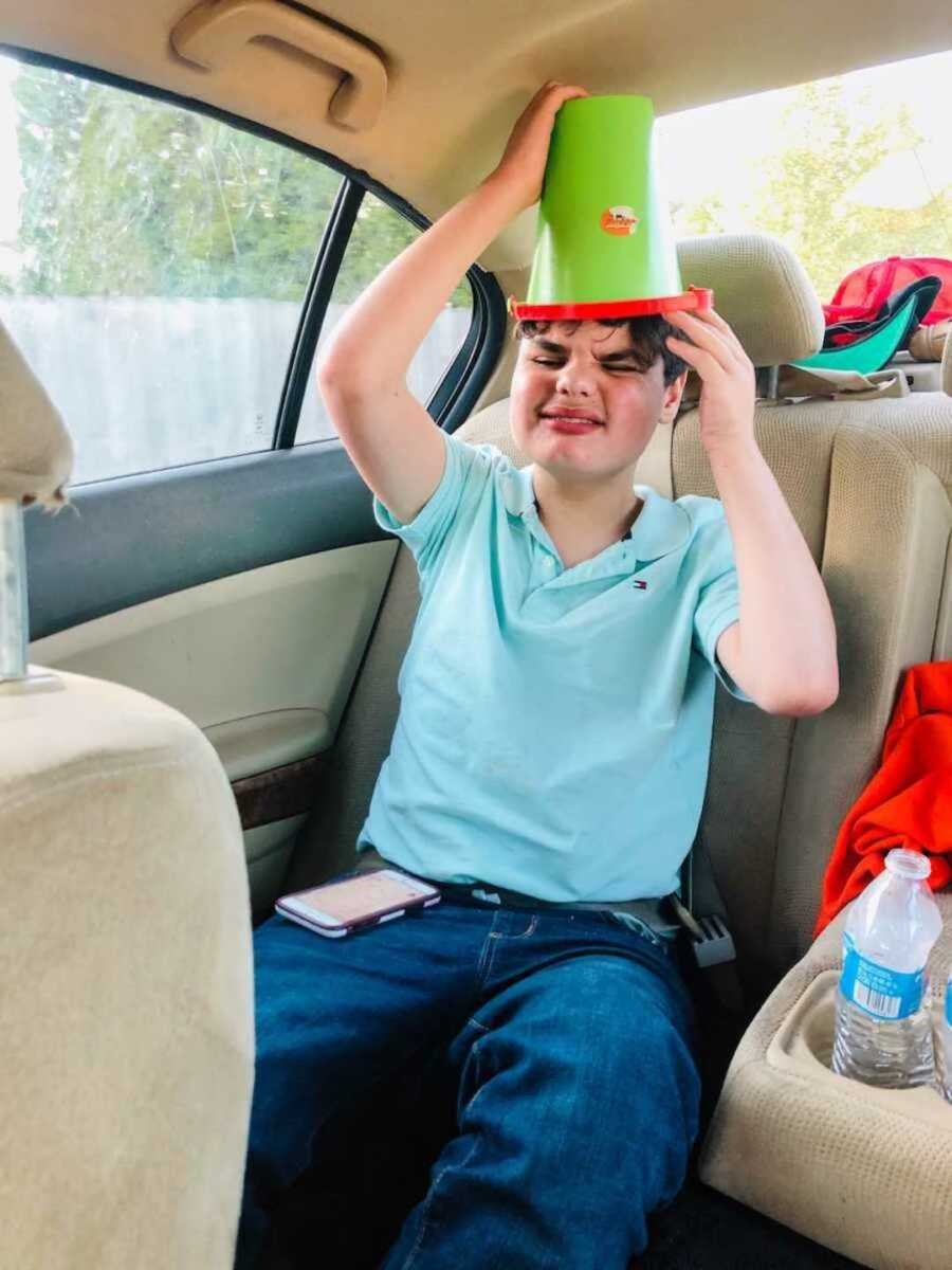 Boy with autism wearing green bucket as hat