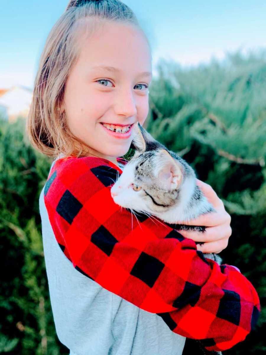 Little girl smiling as she holds a white and brown cat