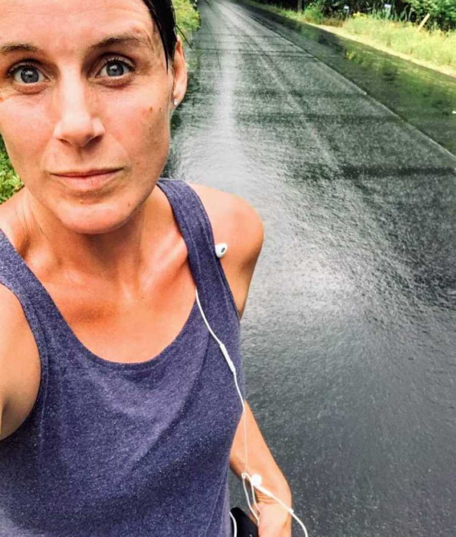 Woman on run stands on side of road and takes a selfie
