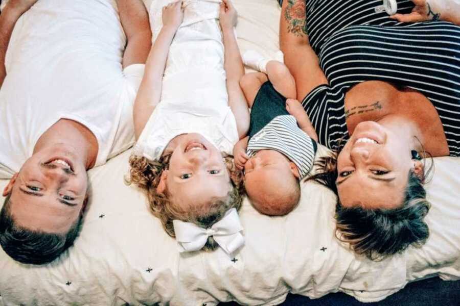 Family lying down on white duvet cover together