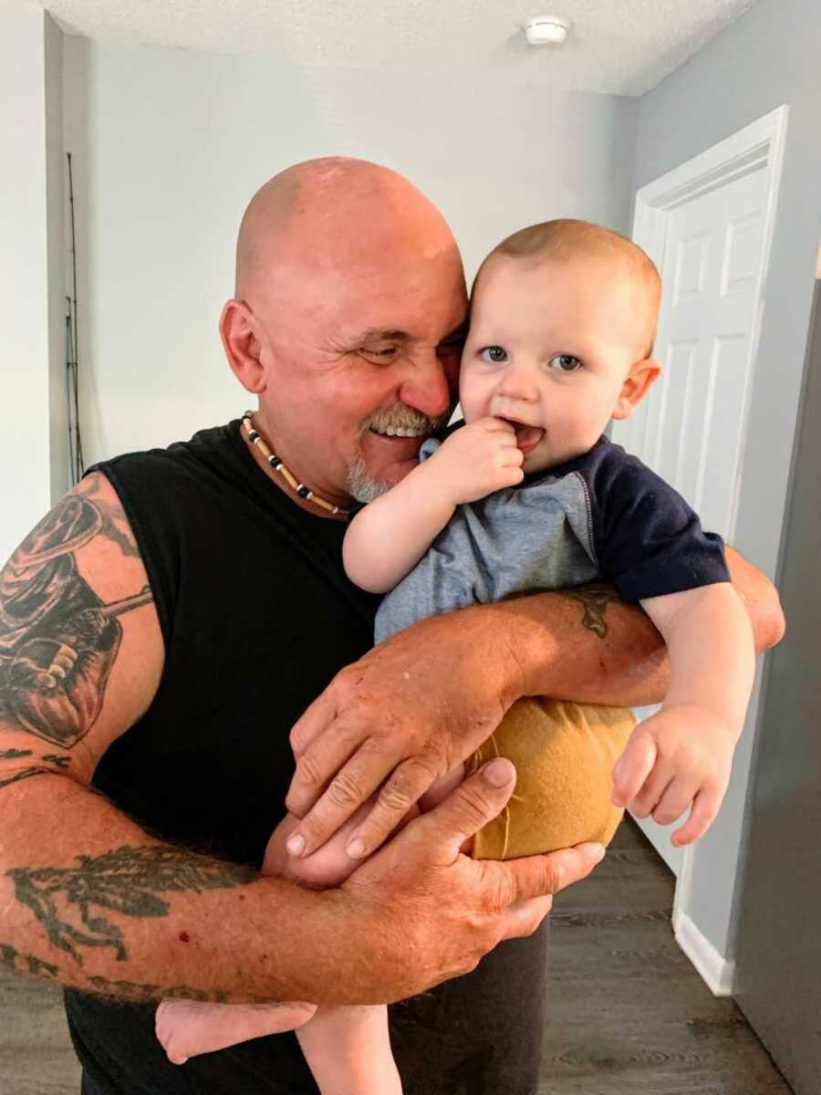 Smiling grandfather holding newborn son