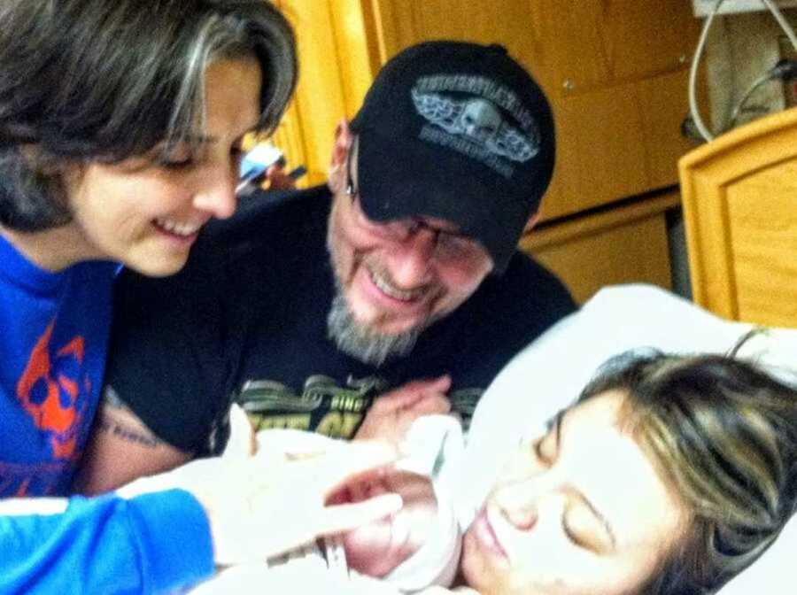 Teen mom holding newborn baby next to parents