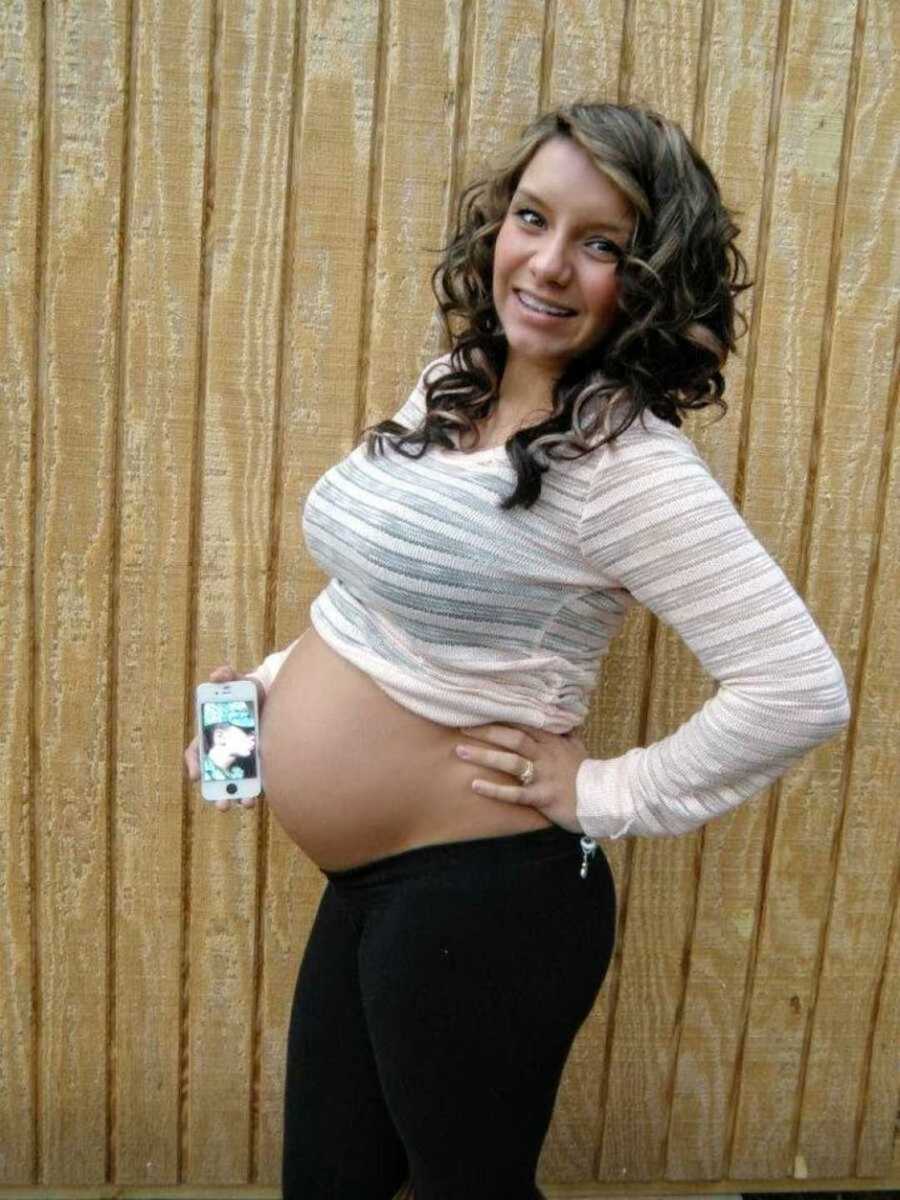 Military spouse holding iPhone to her pregnant belly