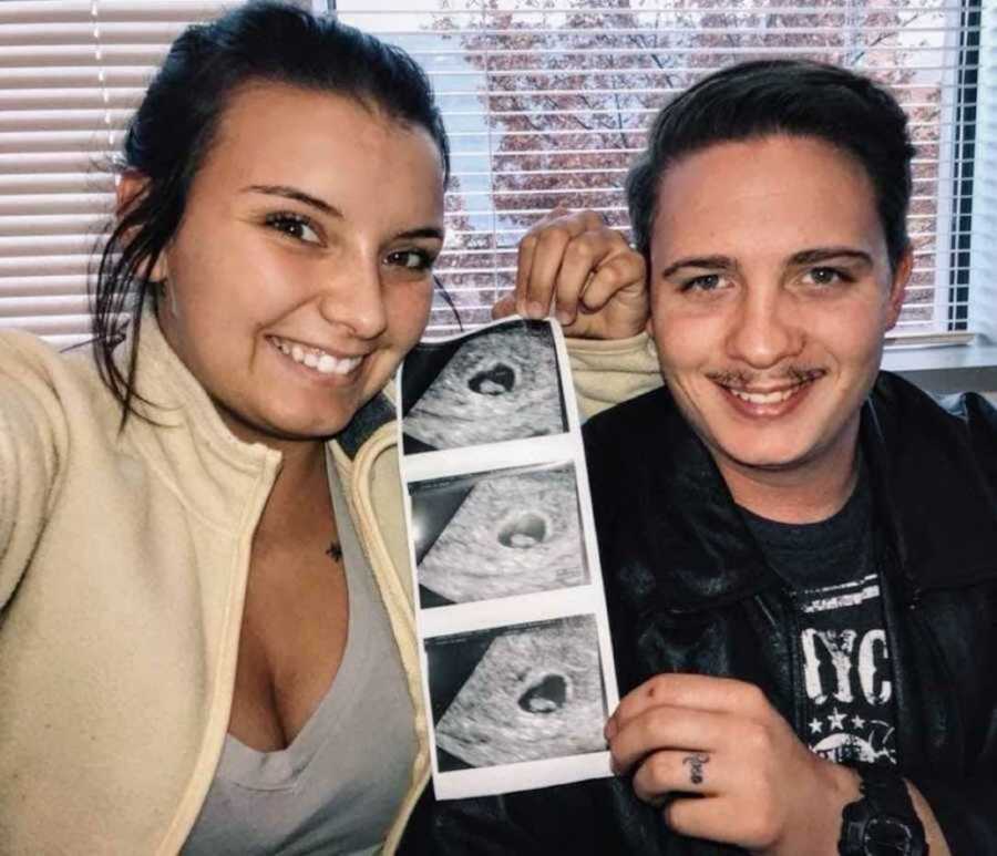 Young parents holding up ultrasound photos