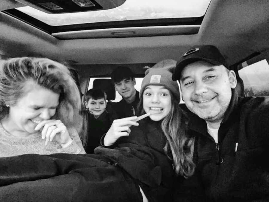 parents take a car selfie with their three teenage children in the backseat