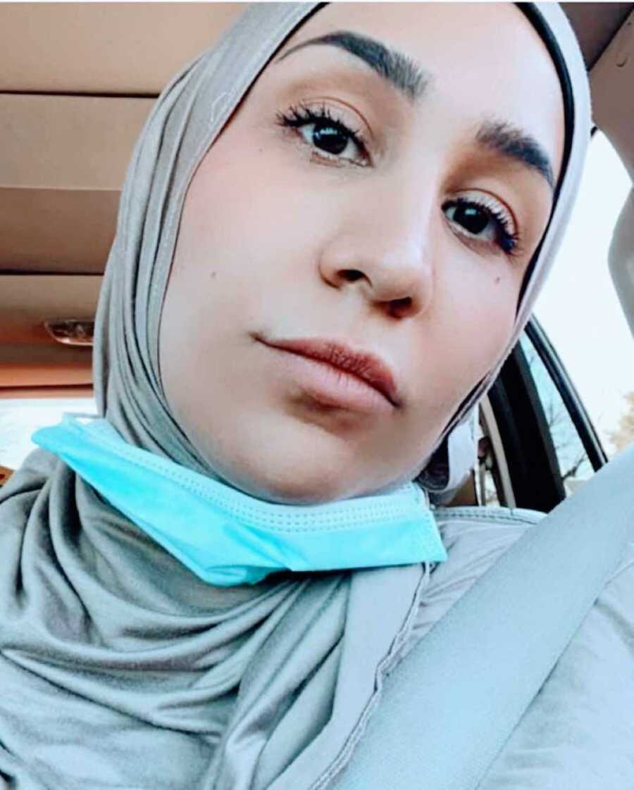 Burnt out mom wearing a hijab takes a car selfie in between running errands