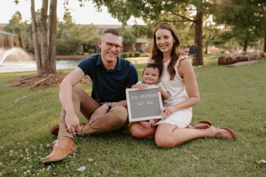 Couple take photo with their adopted son, announcing that they are adopting his baby sibling