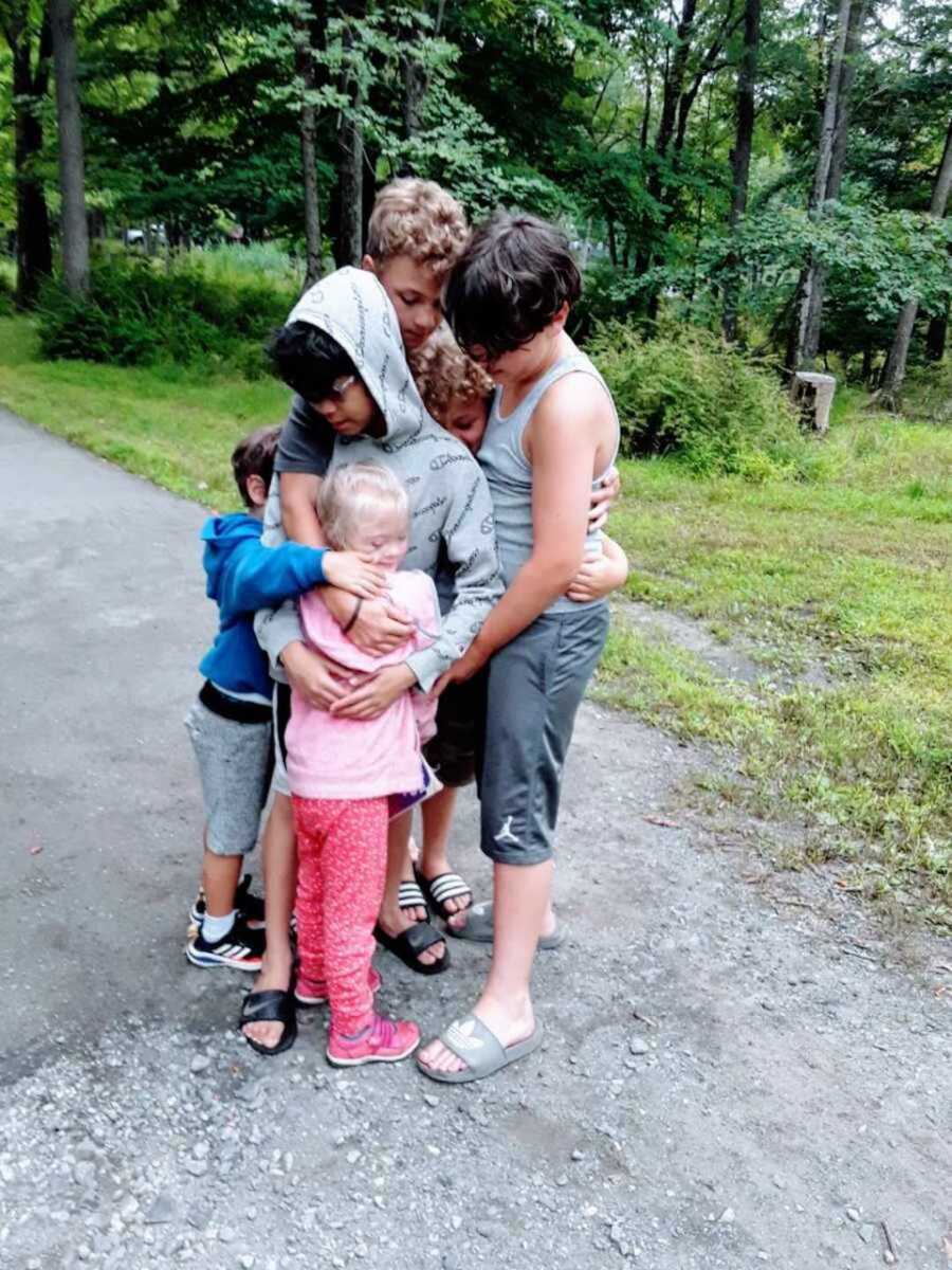 Neighborhood friends hugging little girl with Down syndrome