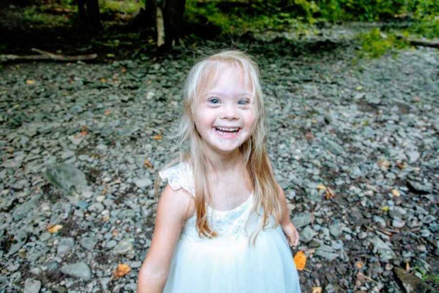 Girl with Down syndrome smiling in forest 