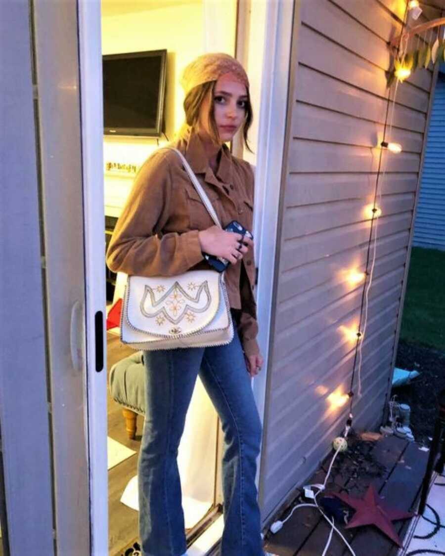 college girl posing in doorway holding a shoulder bag