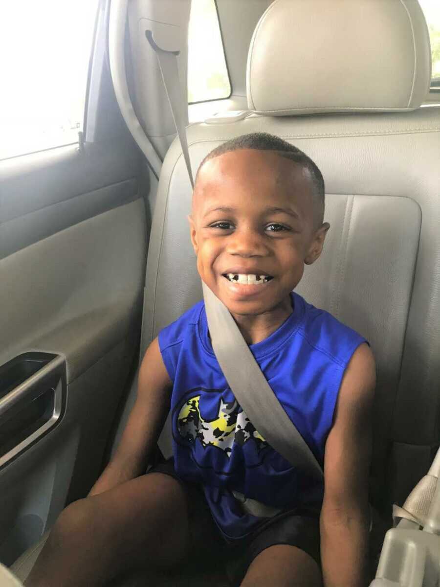 Dwayne sitting in the car wearing a blue outfit with a toothy smile