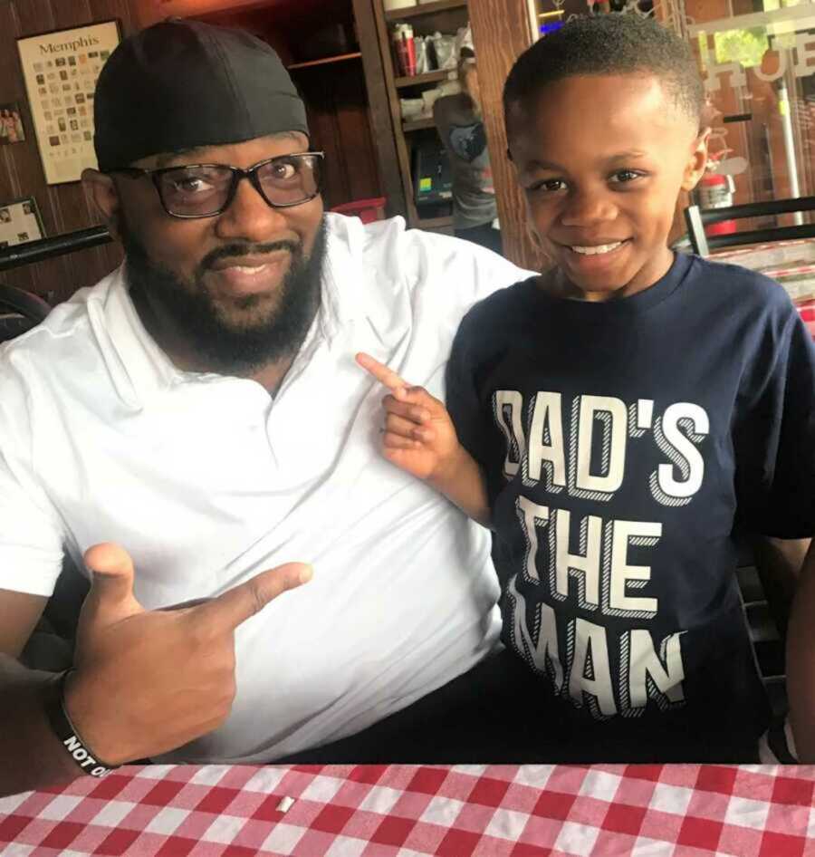 Dwayne points to his dad, smiling as he wears a shirt that says "Dad's the man."