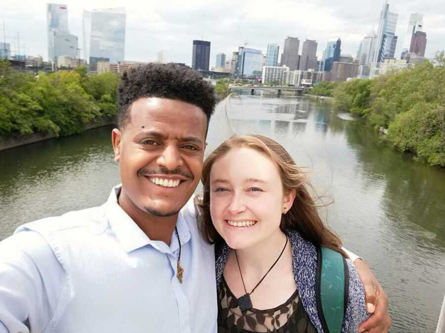 Happy couple smiling in front of a river and the city skyline