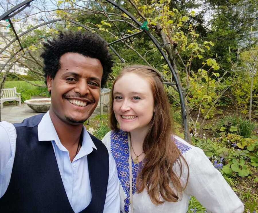 Biracial couple beaming in garden together