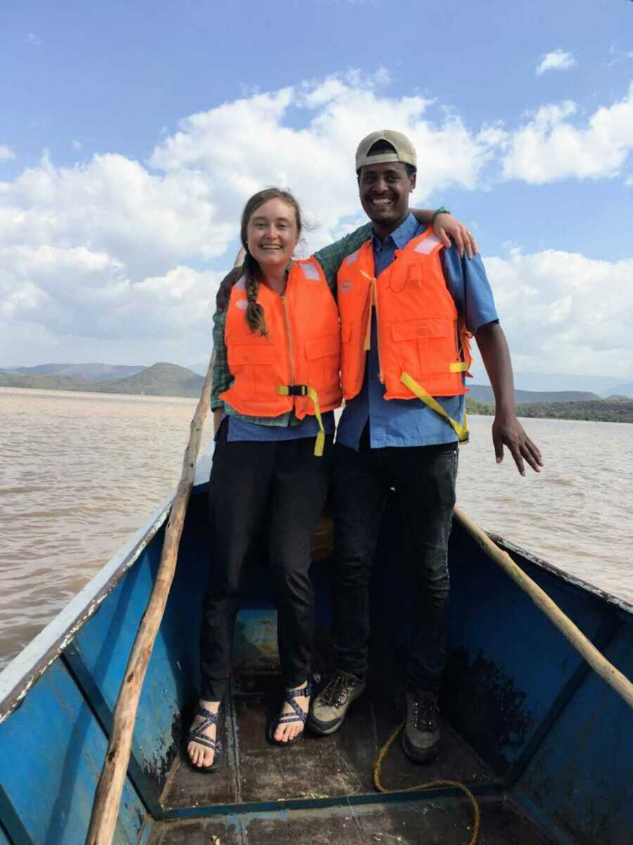 Biracial couple on boat together wearing life jackets 