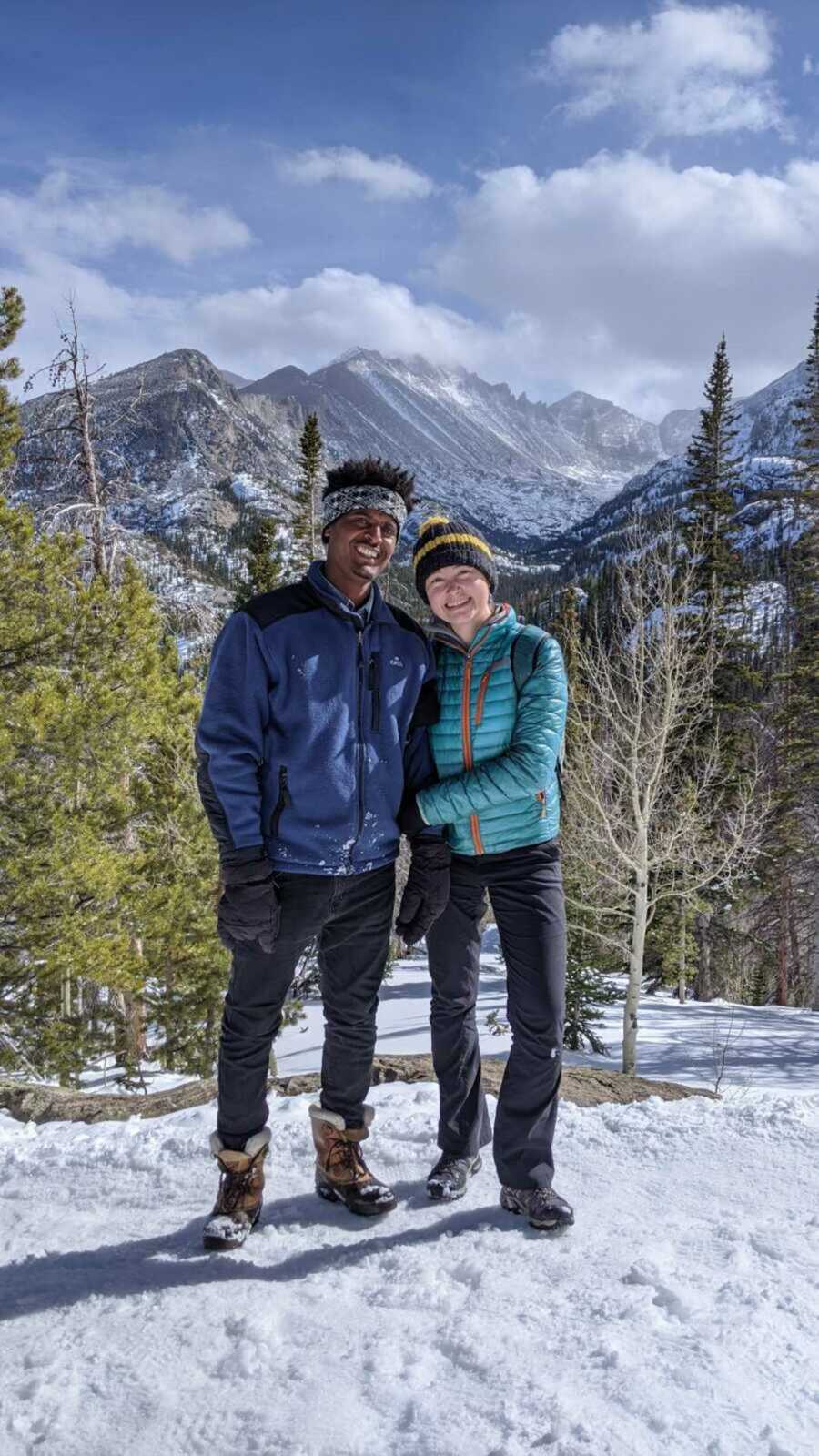 Couple together in the snowy mountains with winter gear on