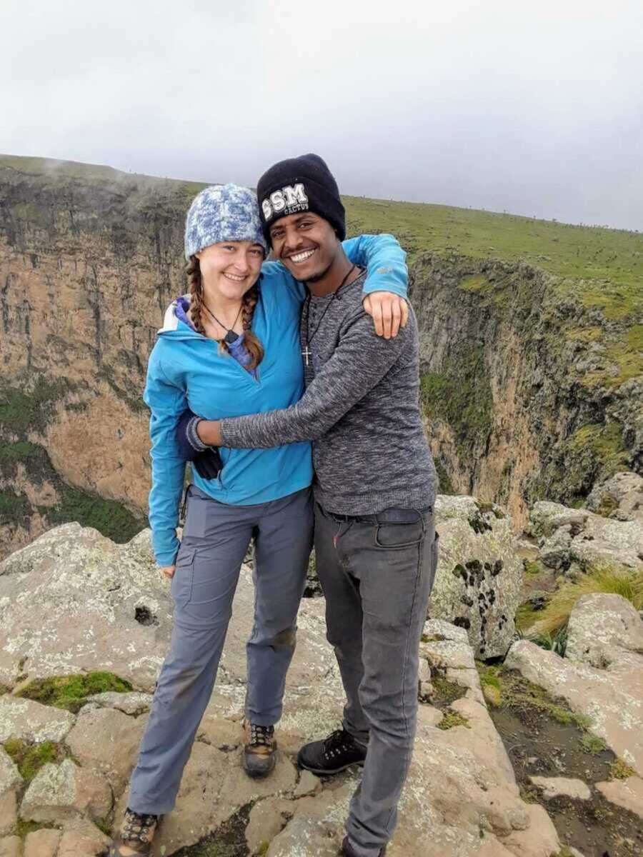Biracial couple embracing one another as they hike