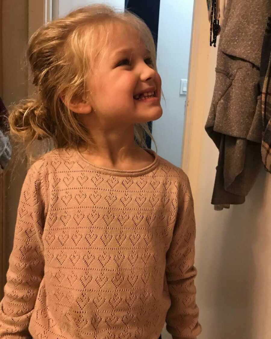 girl with Autism smiles in pink sweater