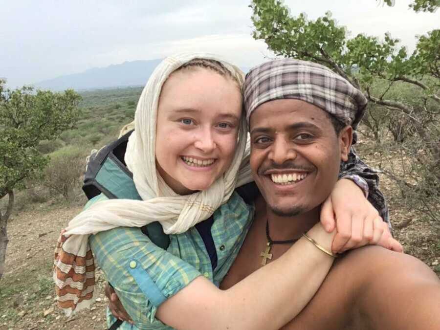 Ethiopian man and American woman smiling together as she embraces him