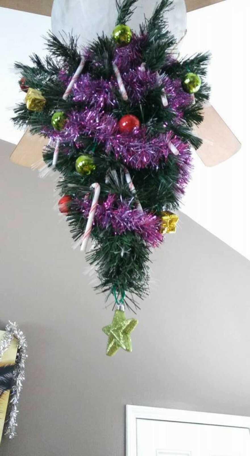 Decorated Christmas tree placed on ceiling fan 