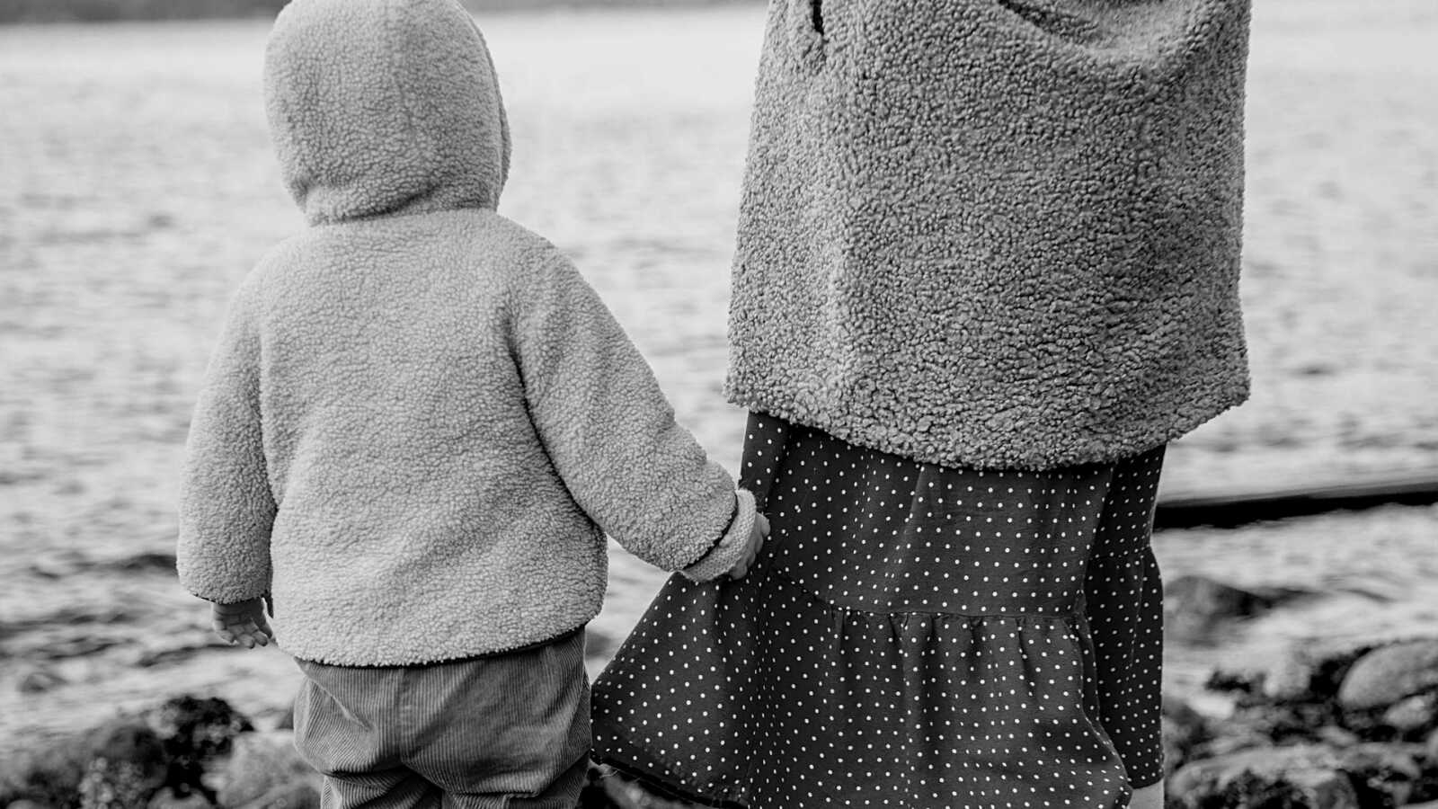 toddler walking next to mom and holding her dress