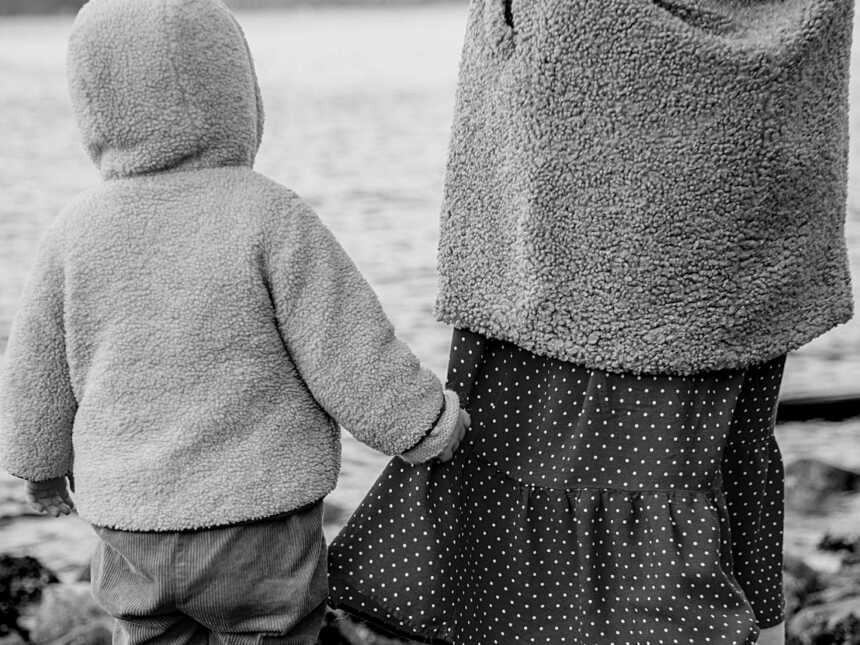toddler walking next to mom and holding her dress