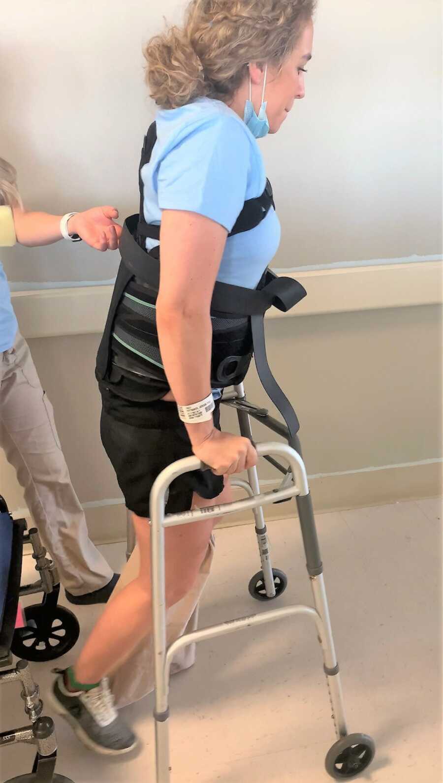 Young woman walking with walker at the hospital while recovering from skydiving accident 