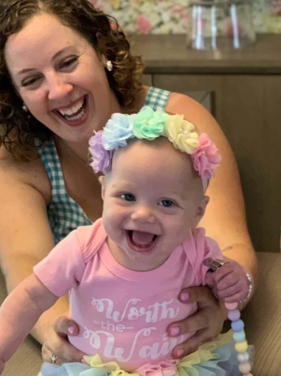 Adoptive mom playing with toddler daughter wearing a pink shirt and rainbow flower headband