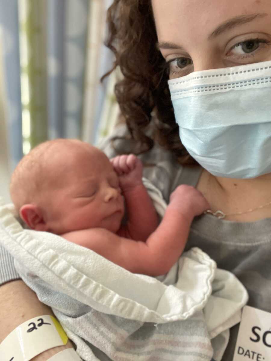 adoptive mother in blue mask with newborn resting on chest 