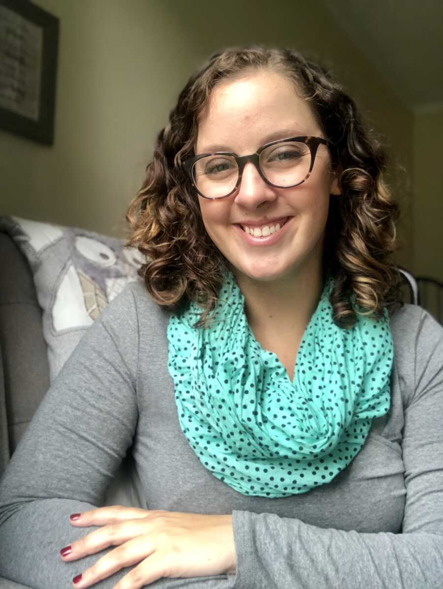 smiling adoptive mother wearing grey long sleeve and teal polka dot scarf with glasses 