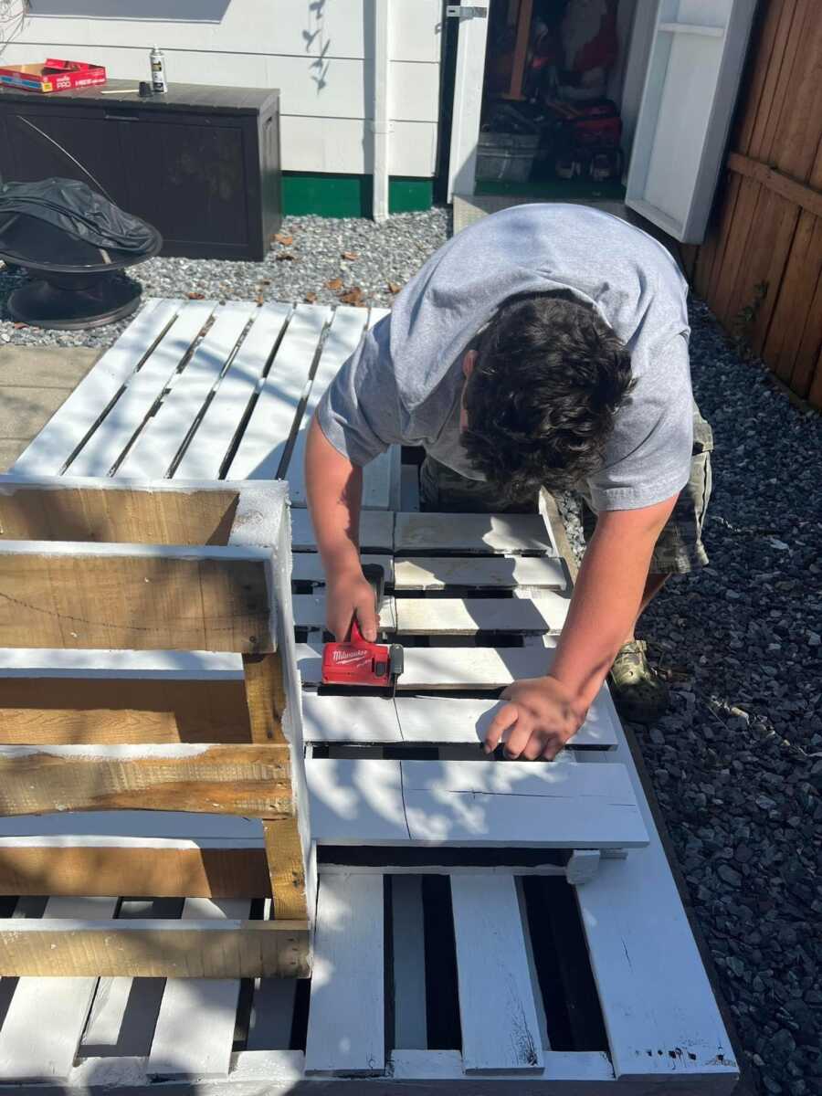 Autistic son working on building a white fence 
