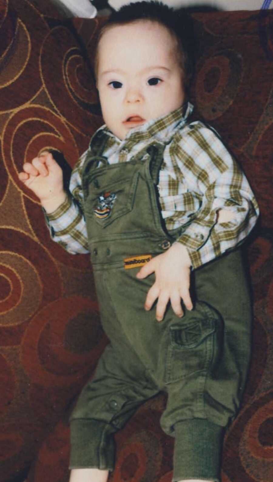 adopted son with Down syndrome wearing green overalls
