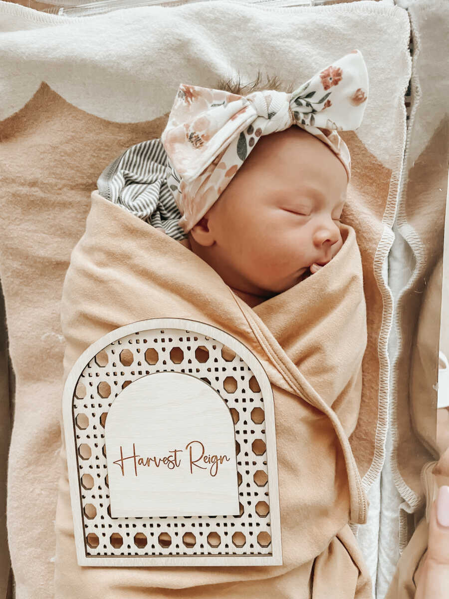 close up of newborn babygirl swaddled in tan blanket sleeping