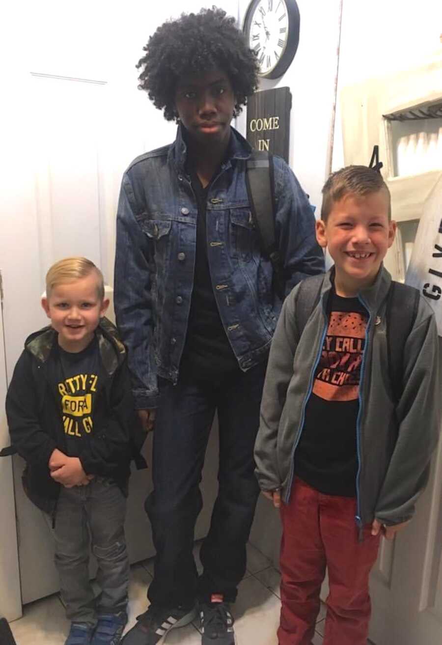 three brothers stand together while wearing backpacks, ready for school