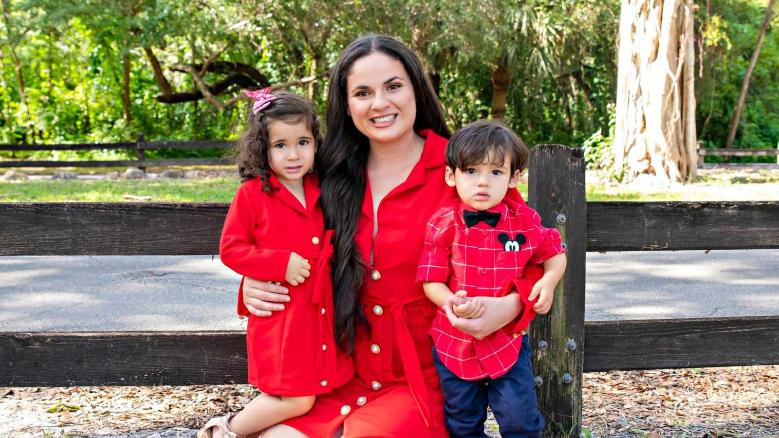 co-parenting mom poses with two children in red outfits