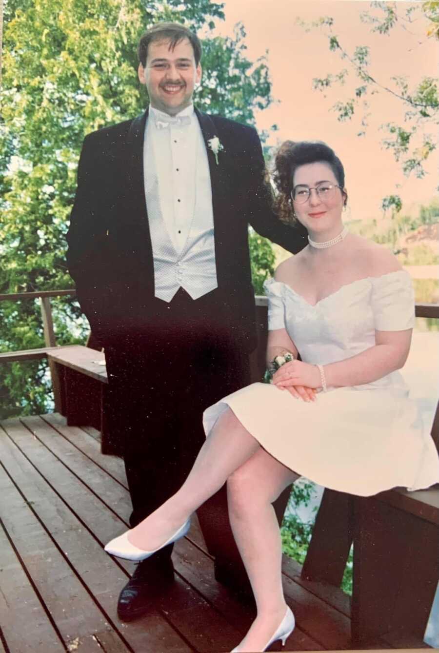 couple together on their wedding day, husband has hand on wife's shoulder