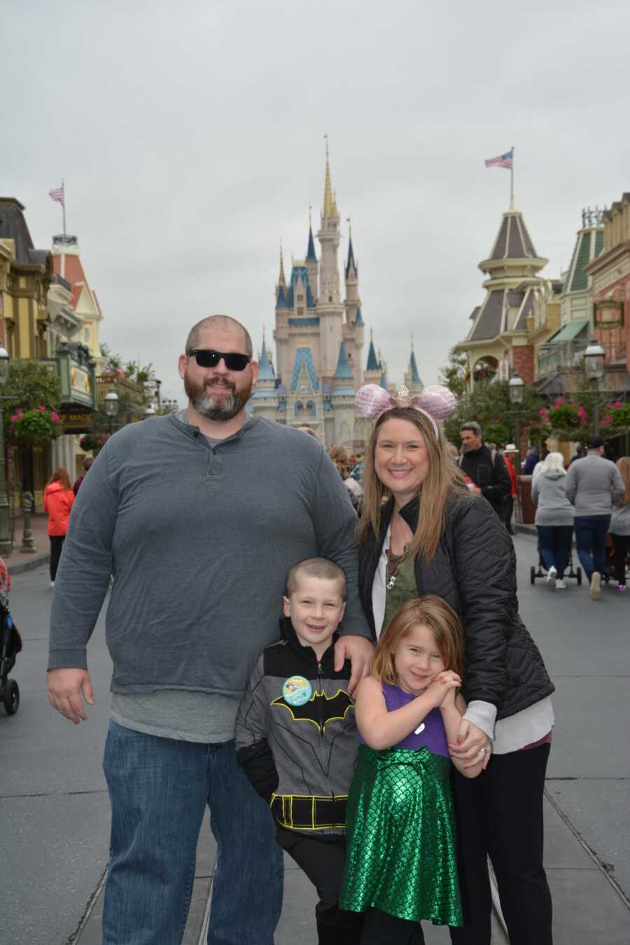 family of four standing in front of Cinderella castle at Disney World