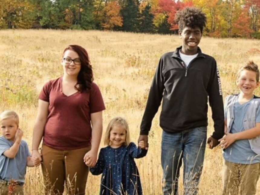 siblings through adoption stand together hand in hand in an open field
