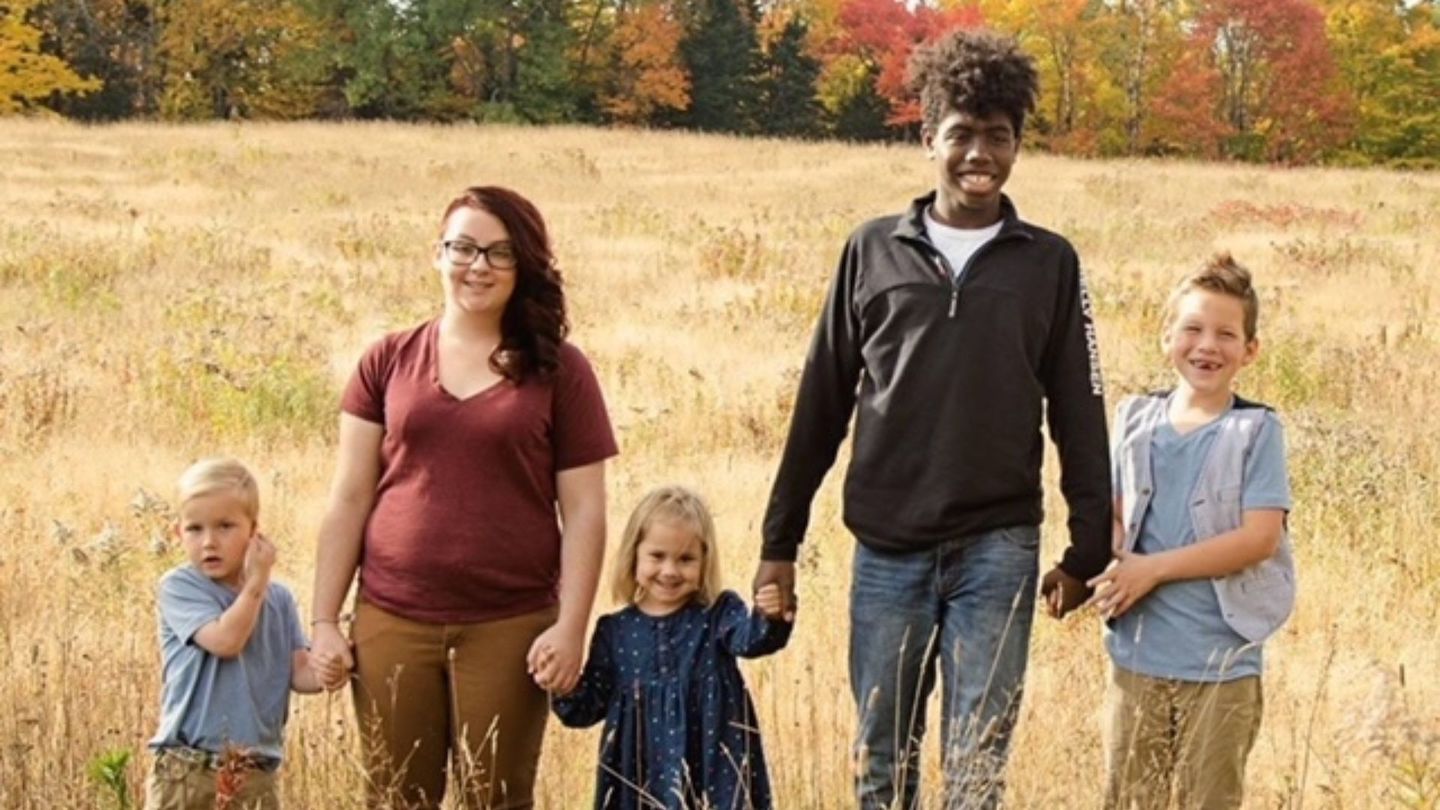 siblings through adoption stand together hand in hand in an open field