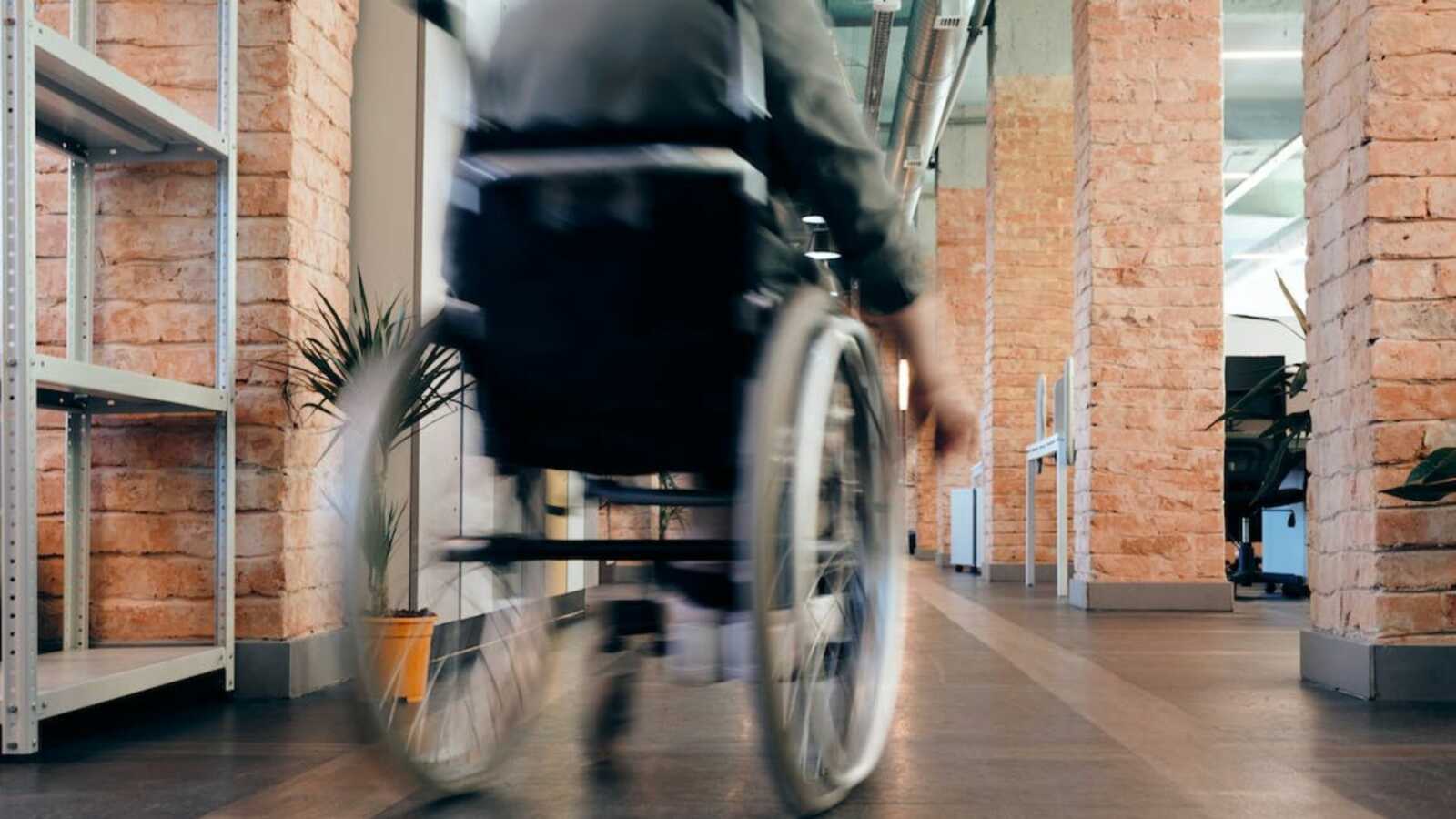 Man rolling in wheelchair down hallway
