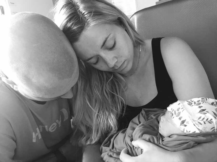 Mom holding her newborn baby girl after giving still born birth with father next to them