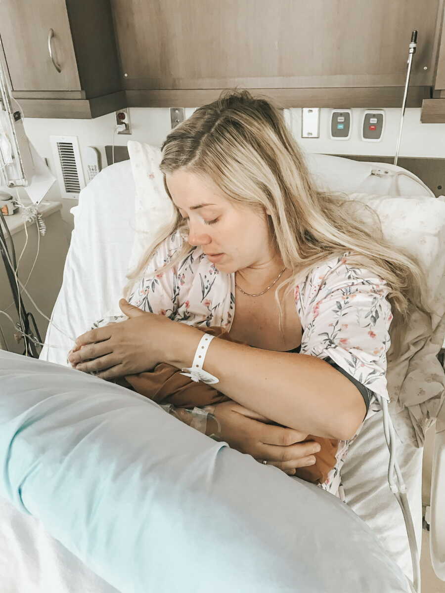 Mom holding her newborn baby girl in hospital bed after giving birth