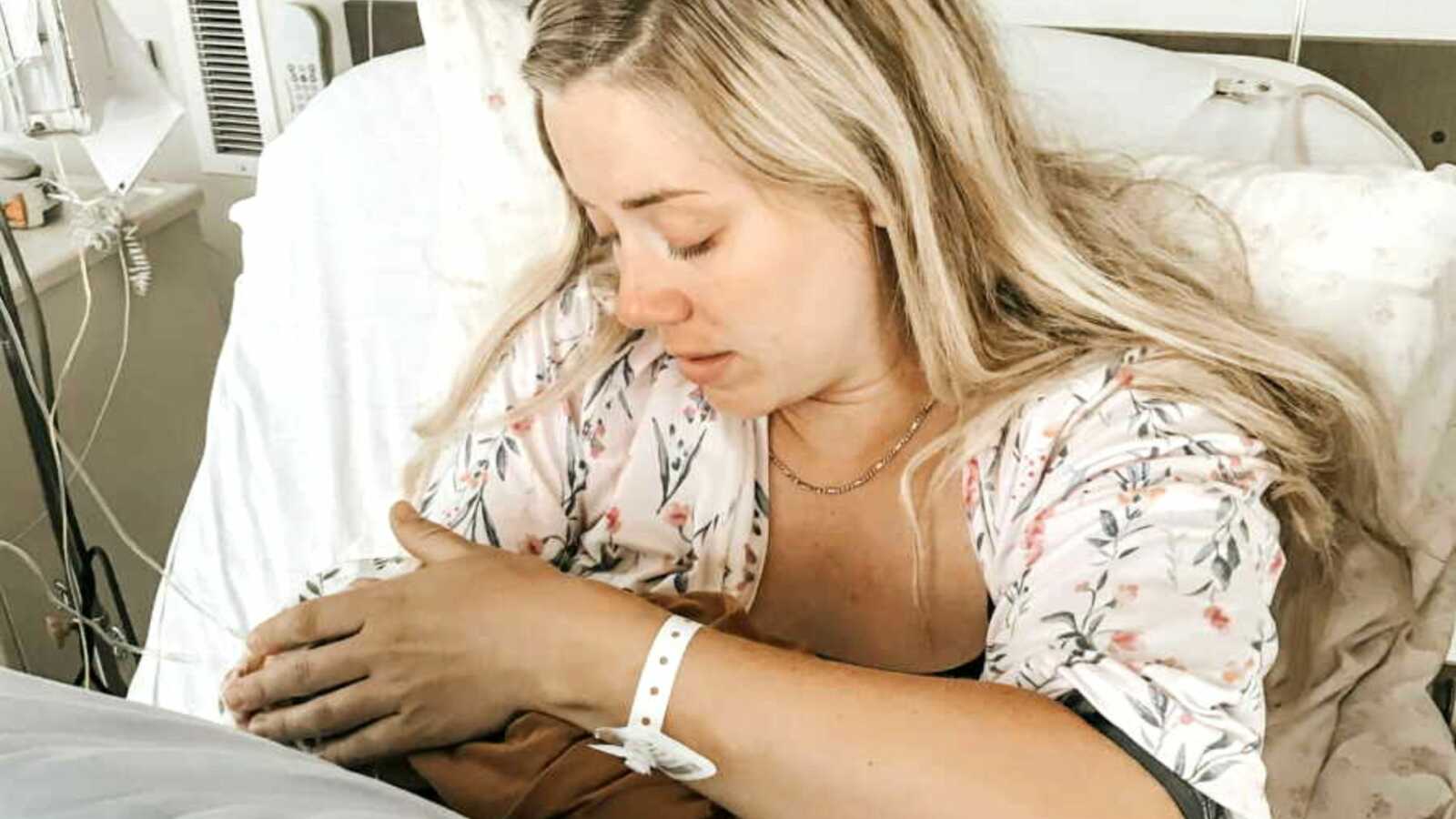 Postpartum mom holding stillborn daughter in hospital bed