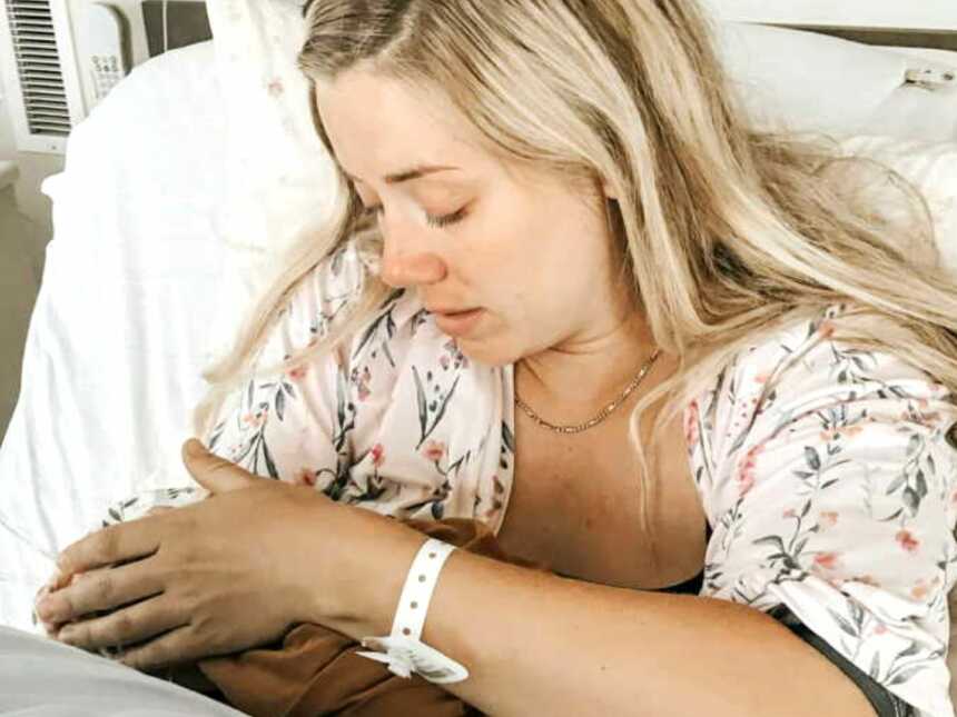 Postpartum mom holding stillborn daughter in hospital bed