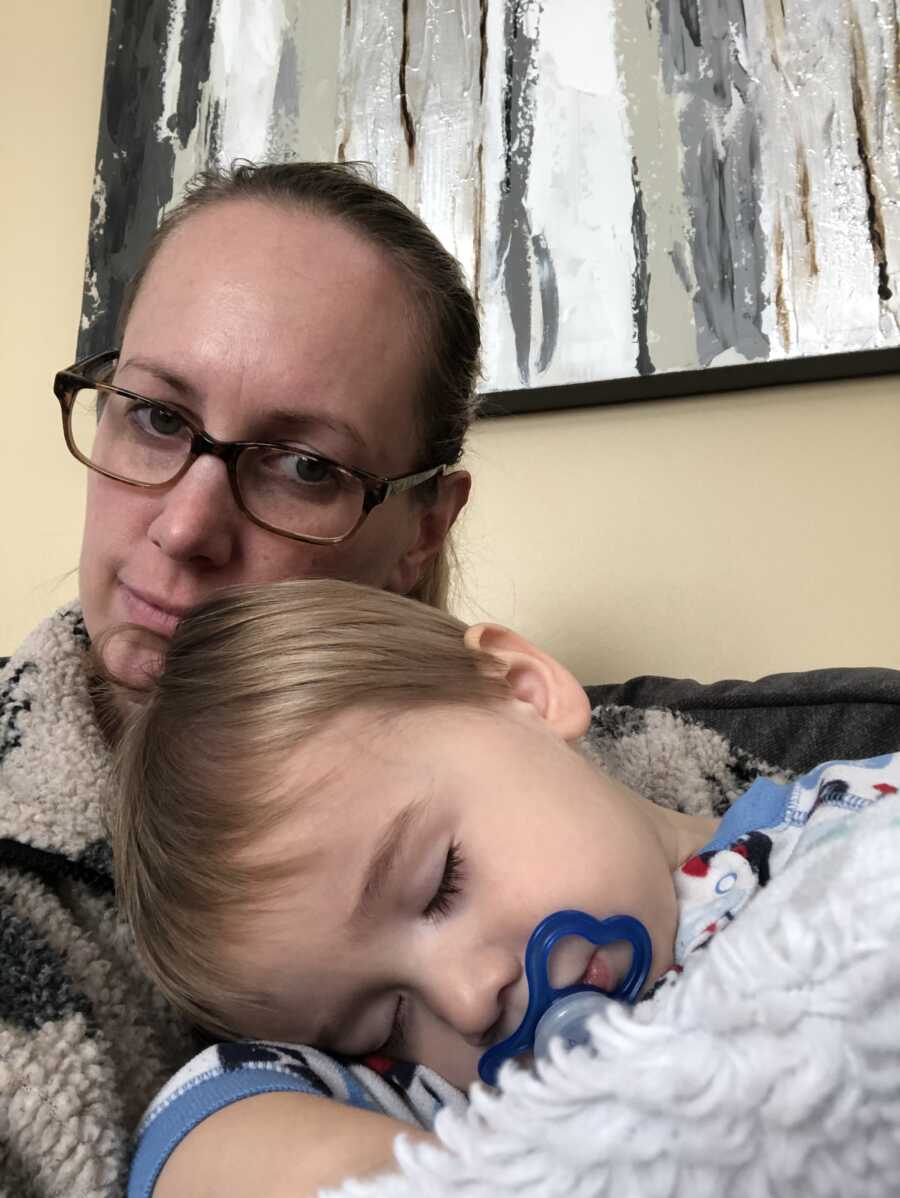 mom wearing glasses and sweater sewn by grandmother with her son sleeping on her chest