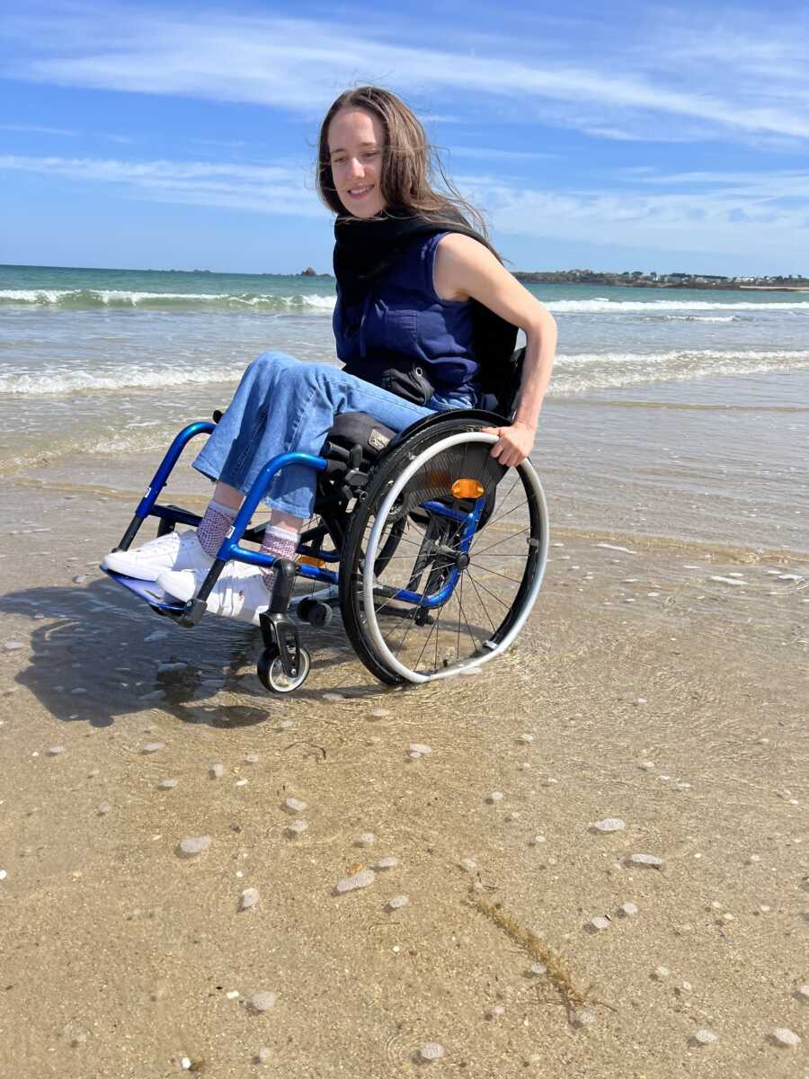 Paraplegic woman in front of ocean on beach in wheelchair